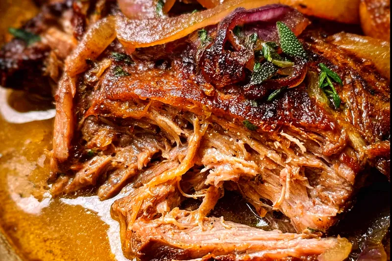 Apple cider braised pork shoulder bubbling gently in a Dutch oven with caramelized onions and apple slices, showing the perfect braising technique
