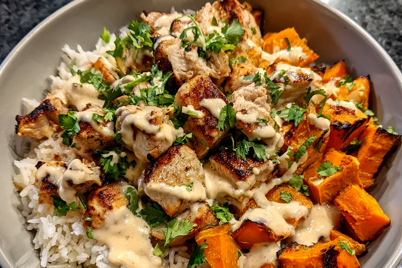 An assortment of fresh ingredients including chicken breast, sweet potatoes, spinach, and avocado displayed beautifully.