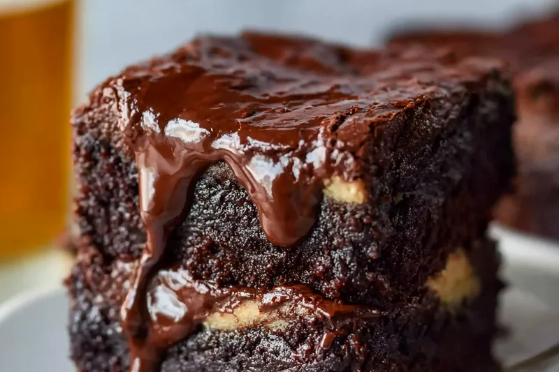 Organized layout of brownie ingredients including flour, sugar, cocoa powder, cream cheese, eggs, and butter in glass bowls on white marble surface