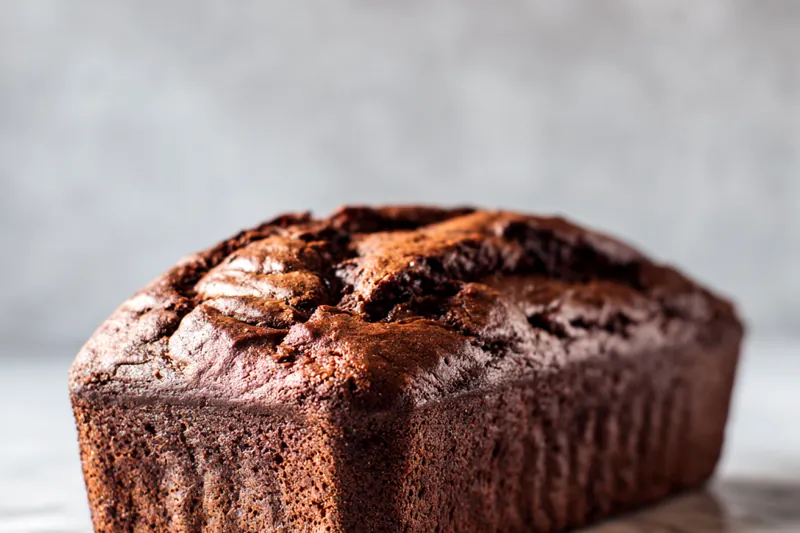 Pouring batter into a loaf pan for baking.