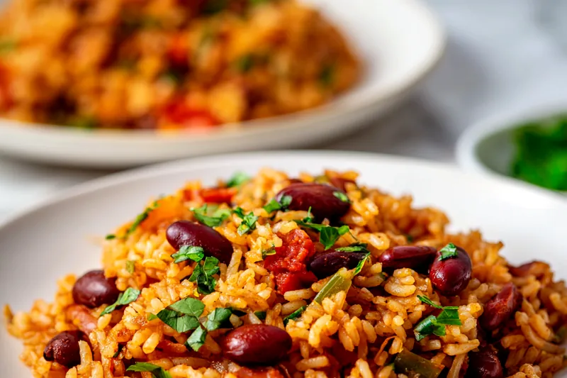 Mediterranean rice and beans simmering in a large pot with visible beans, rice, and vegetables, steam rising from the aromatic dish
