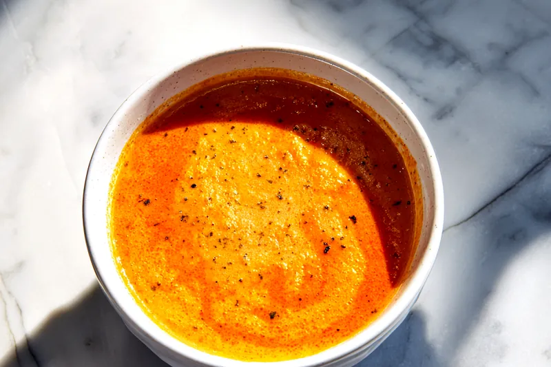 Fresh ingredients for roasted red pepper gouda soup including red peppers, onions, garlic, and gouda cheese.